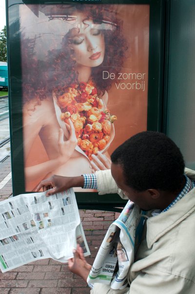 Man reading a newspaper in Brussels tram train stop in Brussels, Belgium by Unbekannt Unbekannt